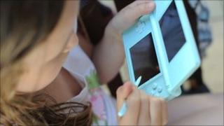 Девушка играет в портативные компьютерные игры Nintendo DS Lite