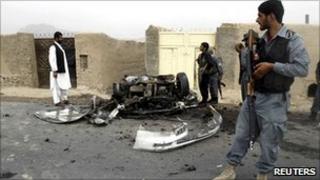 An Afghan policeman keeps watch at the site of a blast in Dand district of Kandahar province