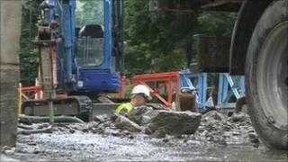 Workman standing in a trench on Lower Bristol Road, Bath