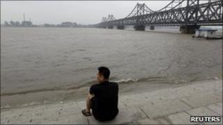 A Chinese resident looks at the rising water level of Yalu River opposite the North Korean town of Sinuiju