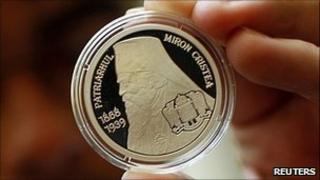 A man holds up a coin depicting Romania's late Patriarch Miron Cristea, who led the Romanian Orthodox Church from 1925 to 1939