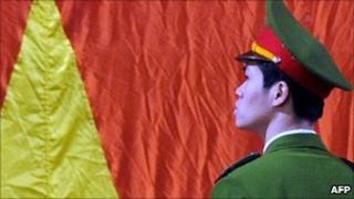 File image of a policeman in Hanoi standing in front of the Vietnamese flag