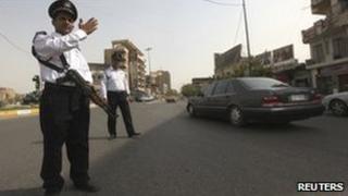 A policeman armed with a Kalashnikov directs traffic in Baghdad, 6 August
