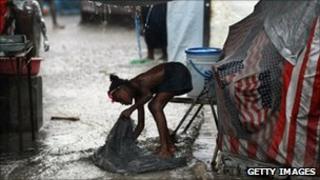 A young girl washes out a sack as heavy rain hits Haiti on 17 August