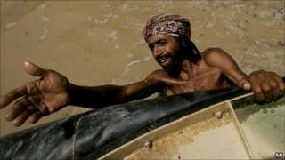 Pakistani flood survivor hangs onto a hovercraft, waiting to get food from naval officials in Sangi Village near Sukkur (19 August 2010)