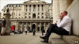 An office worker talks on a mobile phone outside the Bank of England