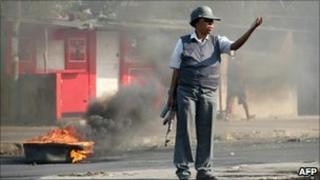A policewoman by a burning tyre in Maputo, Mozambique (2 September 2010)