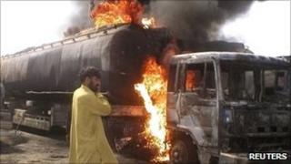 Truck driver watches as fuel tankers burn after they were set ablaze at Sibi, in the Balochistan area of Pakistan