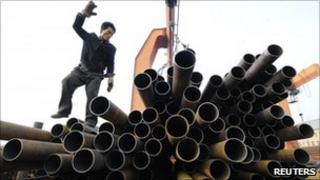 A labourer directs a crane to lift pipes at a steel market in Taiyuan, Shanxi province