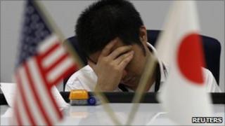 A foreign exchange dealer reacts at a trading room in Tokyo
