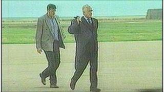 Men in suits walking along road