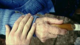 Elderly patient and carer hold hands