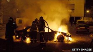 Firefighters try to extinguish a car after rioting in Clichy-sous-Bois (30 October 2005)
