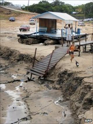 People walk on the dry river bed in Marina do David, on the outskirts of Manaus