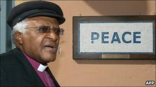 Desmond Tutu walks past a street mosaic which reads "Peace" on the green line that separates the Greek Cypriot side from the Turkish military-controlled areas in the heart of Nicosia (2008)