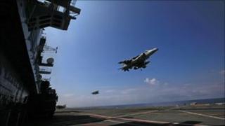 A Harrier jet hovers as it comes in to land on the flight deck of an aircraft carrier
