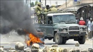 Riot police drive past burning tyre in Dar es Salaam
