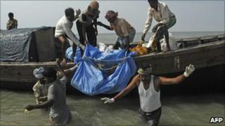 Fishermen carry a recovered body from the waters near Kakdwip, some 100km south of Calcutta, on 2 November, 2010, following the sinking of a ferry on 30 October.