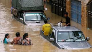 Residents wade through flood water in Hat Yai, southern Thailand, on 3 November 2010