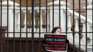 A woman holds a poster reading "Journalist Oleg Kashin has been beaten. I demand to find the persons who attacked him" during a picket at the headquarters of Moscow police department in Moscow on November 7, 2010