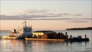 The mosque being shipped along a river