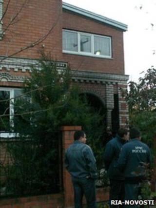 Emergency workers stand outside the house where the murders occurred