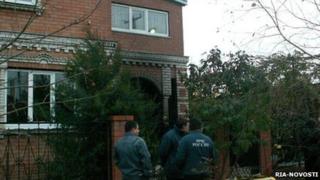 Emergency workers stand outside the house where the murdered occurred