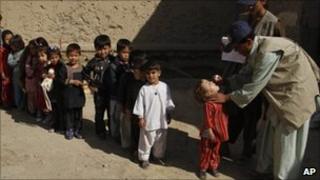 An Afghan health worker gives a polio vaccination to a child, as other children stand on line during a polio campaign in Kandahar province, south of Kabul, Afghanistan on Sunday, Nov 7, 2010