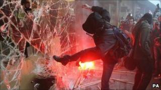 A demonstrator smashes a window at Tory Party HQ