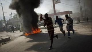 Demonstrators run past burning tyres in Port-au-Prince, Haiti, Thursday, 18 November.