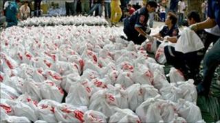 Members of a rescue foundation carry bags of corpses at the mortuary storage room of a Buddhist temple in Bangkok