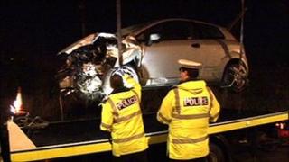 Crashed car being examined by two police officers