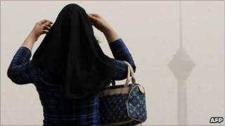 Woman looking at Tehran's smog-bound Milad telecommunications tower in 2009