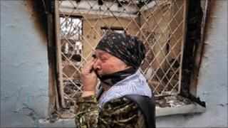 An ethnic Uzbek woman cries as she passes a ruined house in Osh (June 2010)