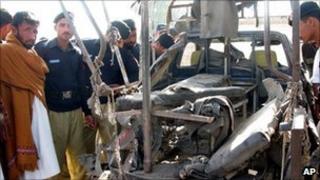 Pakistani police look at a van destroyed by an explosion in Bannu on 30 November 2010