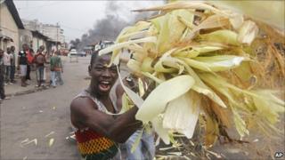 A supporter of Alassane Ouattara throws maize onto a fire in Abidjan