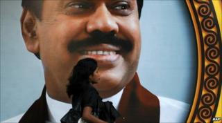 A pedestrian walks past a giant billboard of President Mahinda Rajapaksa on Galle Face promenade in Colombo