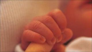 A newborn baby grips the fingers of its mother (generic image)