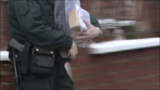 Police officer removing items from home