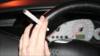 Actor's hand on a steering wheel holding a fake cannabis joint