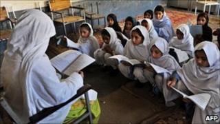 Pakistani female teacher writes on blackboard