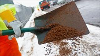 A worker spreads grit, during freezing, cold weather in the UK
