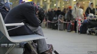 A passenger attempts sleep as Eurostar passengers queue for trains at St Pancras station in London