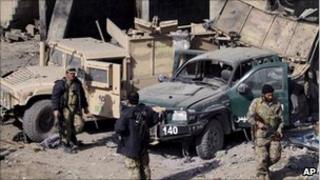Policemen stand near vehicles damaged in Monday's bomb attack