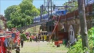 Fire engines stand below the Buenos Aires rail bridge on which a damaged train stands, 31 December
