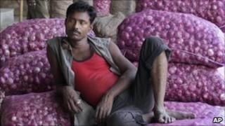 An Indian labourer sits on the sacks of onion at a market in Ahmedabad on 21 December 2010