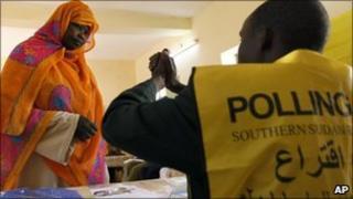 A polling centre official explains to a Southern Sudanese woman the two voting signs contained in the ballot, separation and unity, at a polling centre during the third day of the referendum in the city of Um Durman, Sudan