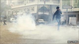 Протестующие проходят через слезоточивый газ во время столкновений с ОМОНом в центре столицы Туниса 14 января 2011 года.