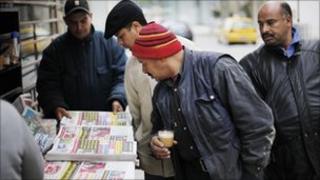 Men look at newspapers at a street kiosk in downtown Tunis