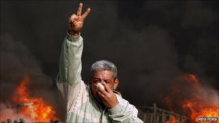 Протестующий жесты перед горящей баррикады во время демонстрации в Каире.Фото: 28 января 2011 г.